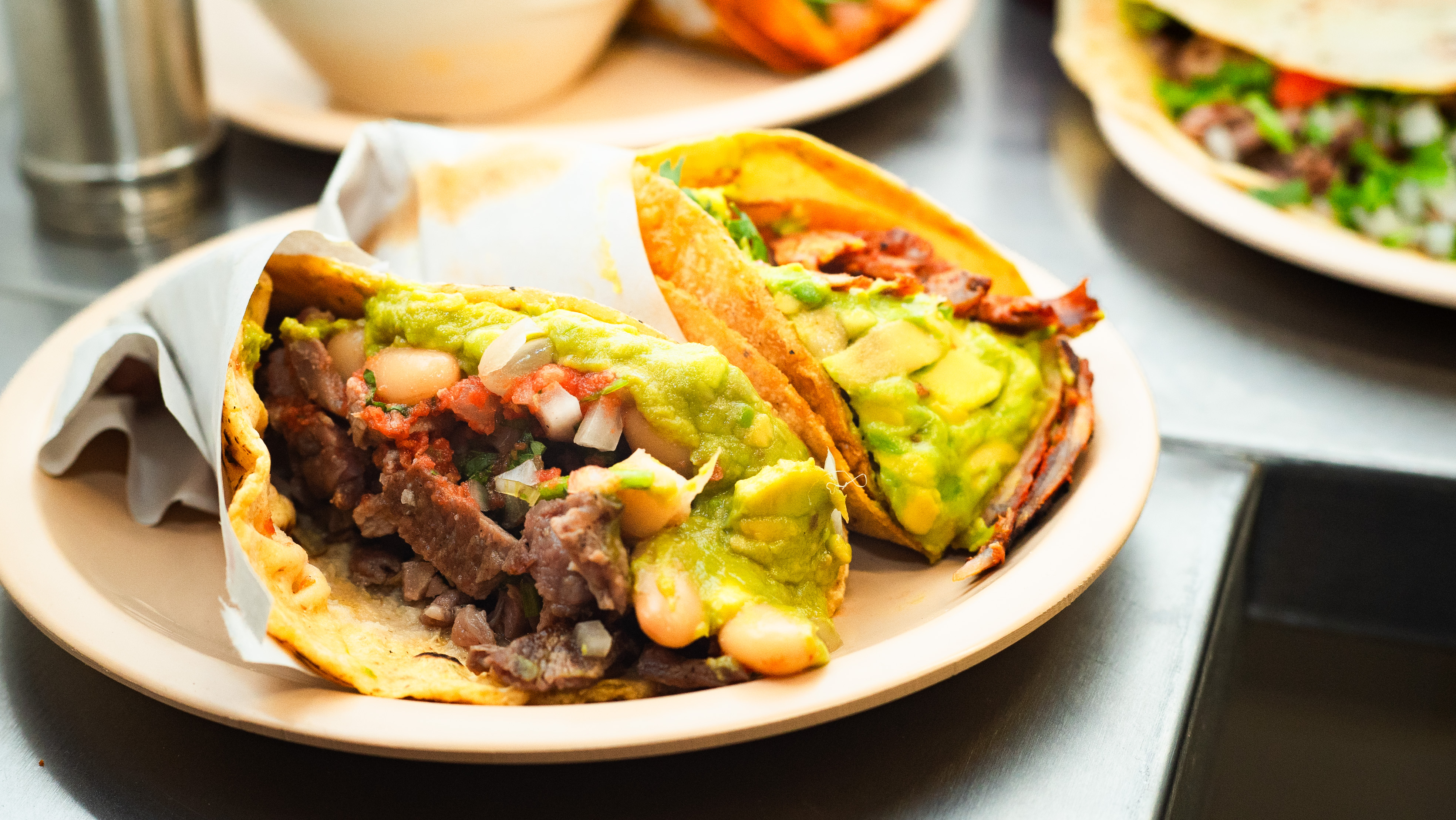 Two tacos overflowing with meat and guacamole.