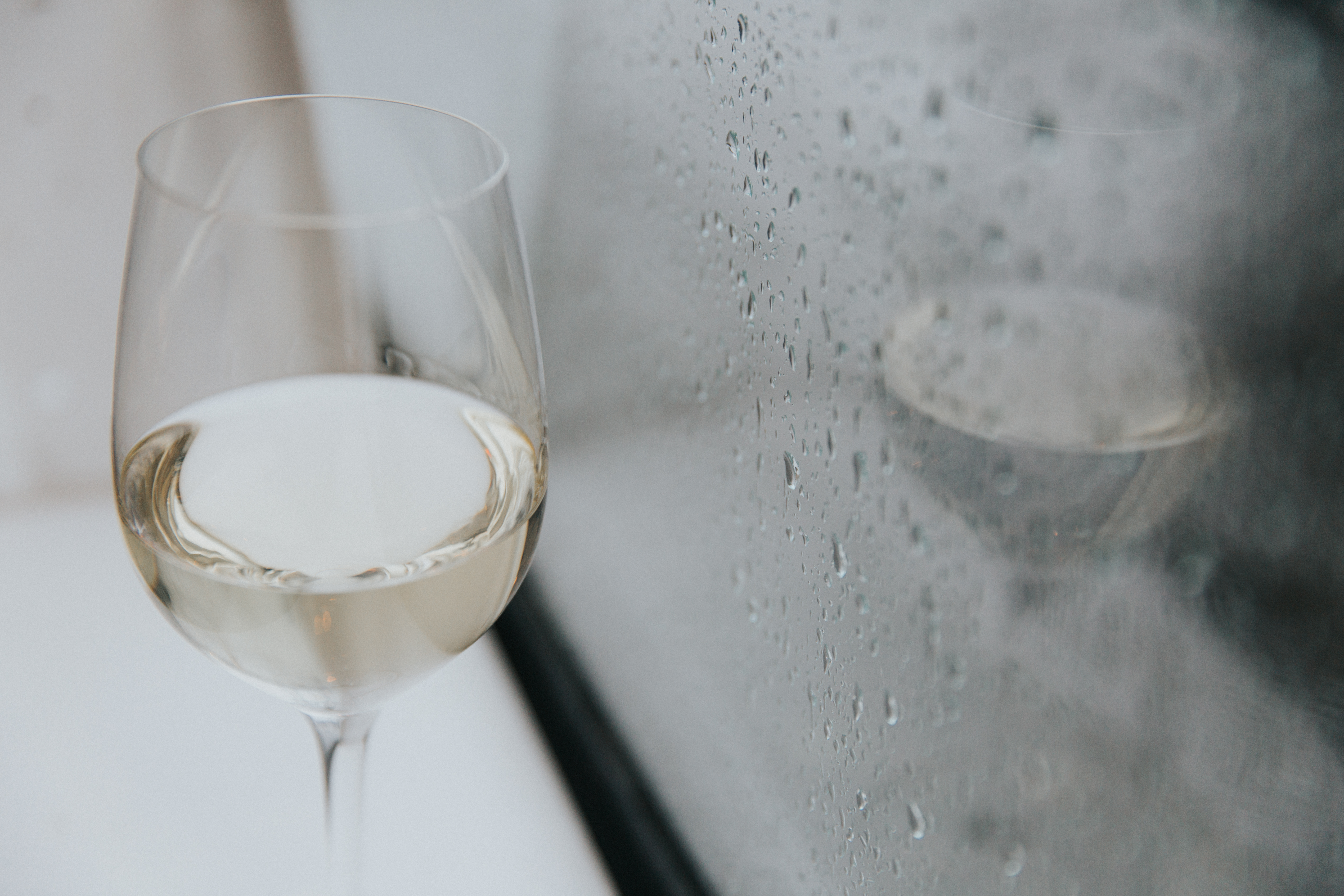 Glass of white wine in front of a rainy window